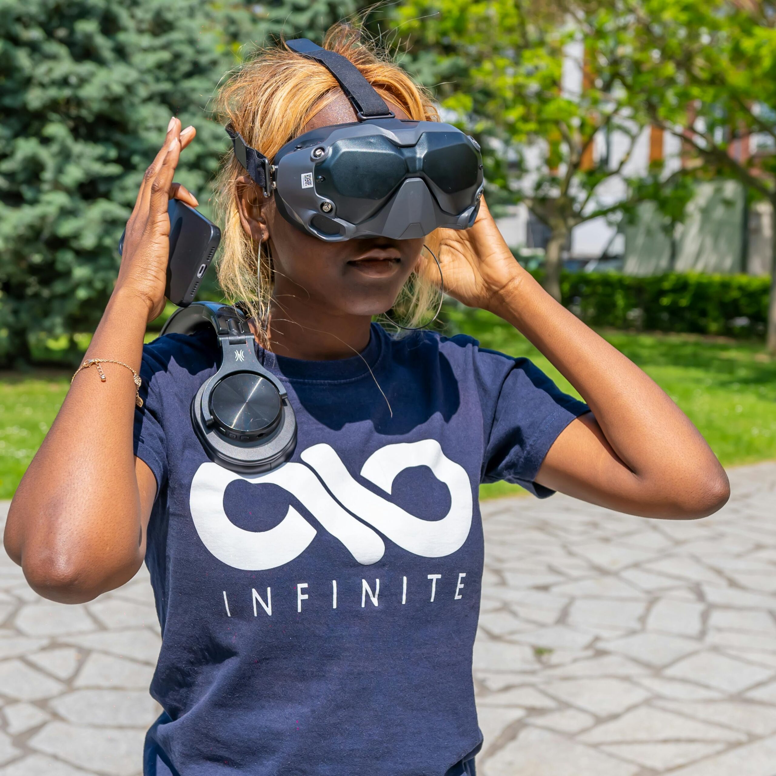 our-services-03 A person wearing a VR headset outdoors, enjoying summer sunlight in a park.