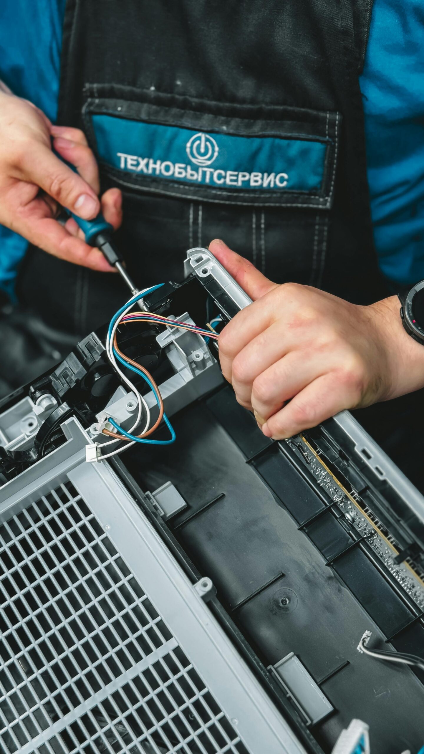 Home Close-up of technician repairing a device, showcasing wiring and tools, ideal for tech and repair themes.