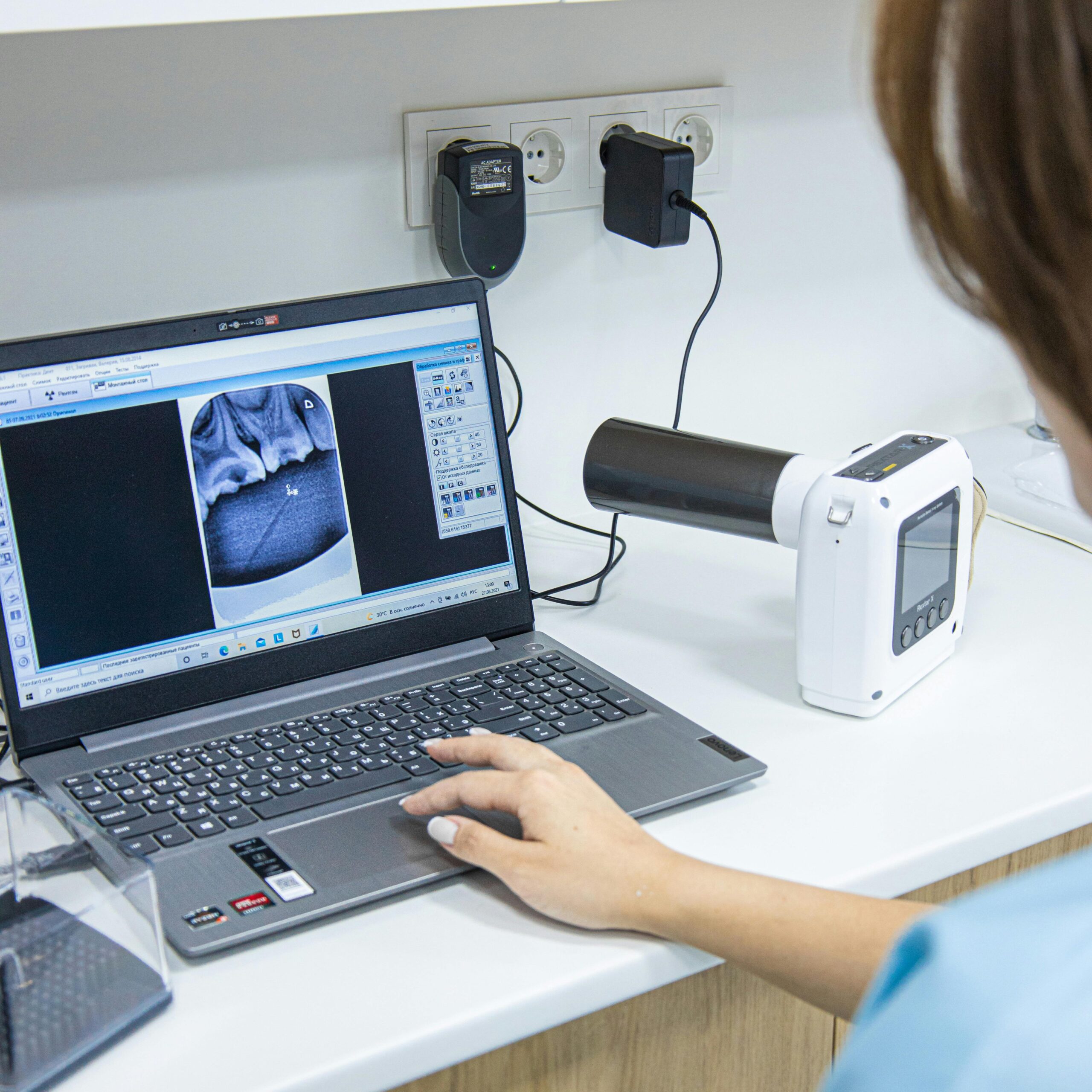 About Medical professional analyzing dental X-ray on laptop in modern clinic.